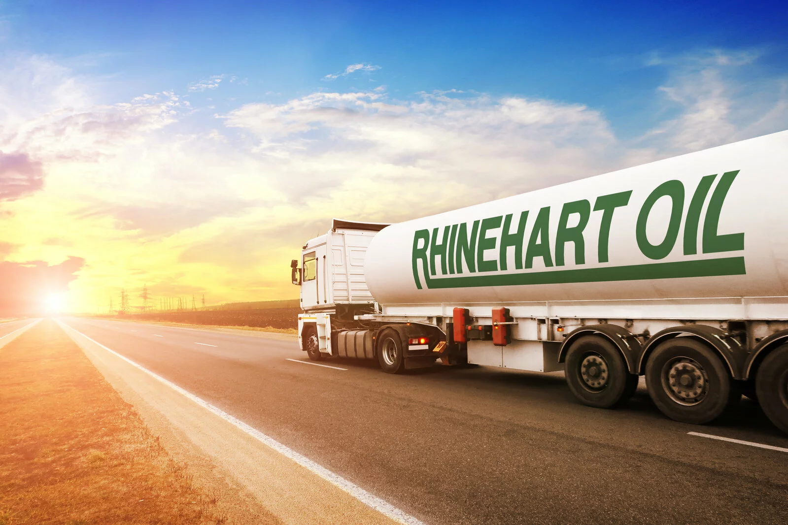 Rhinehart Oil fuel tanker transporting premium fuel and lubricants with the sun going down and a road ahead.